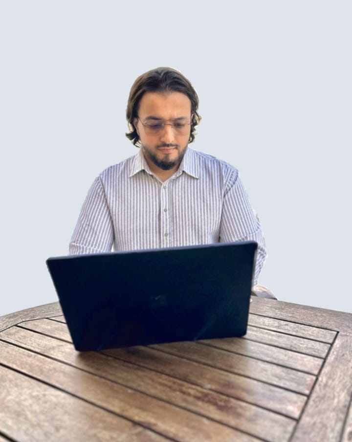 Nas Amar working on a laptop at a table above the beach